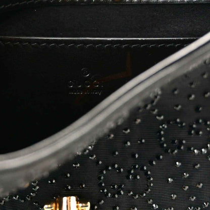 Close-up of black embossed monogram-style pattern on hobo bag with stitched trim.