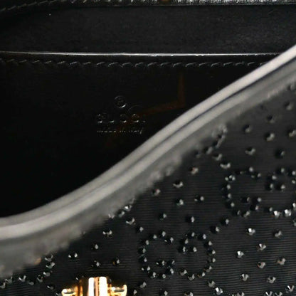 Close-up of black embossed monogram-style pattern on hobo bag with stitched trim.