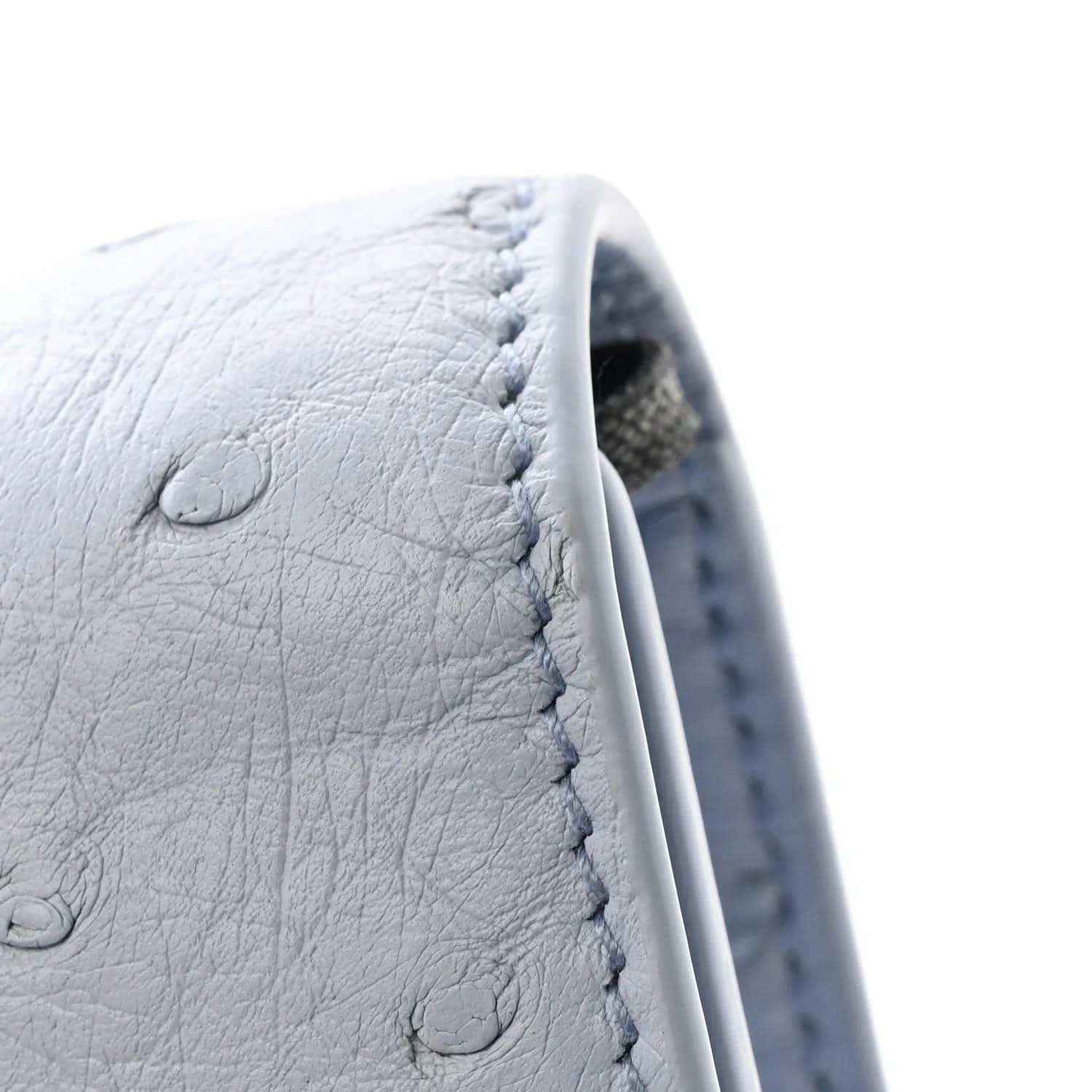 Light blue ostrich leather clutch bag close-up with stitching and embossed texture