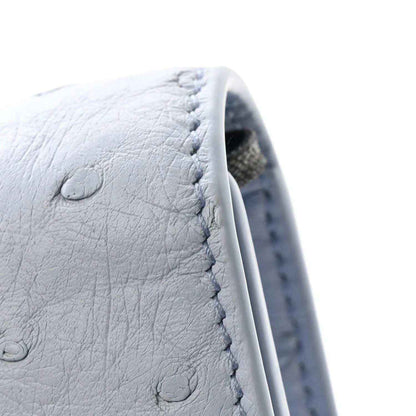 Light blue ostrich leather clutch bag close-up with stitching and embossed texture
