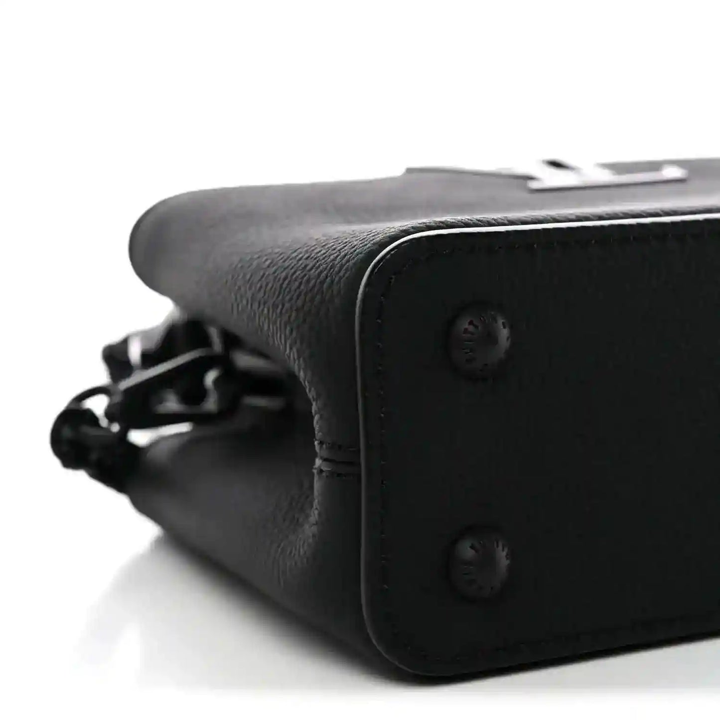 Black mini handbag side close-up with snap buttons and chain strap