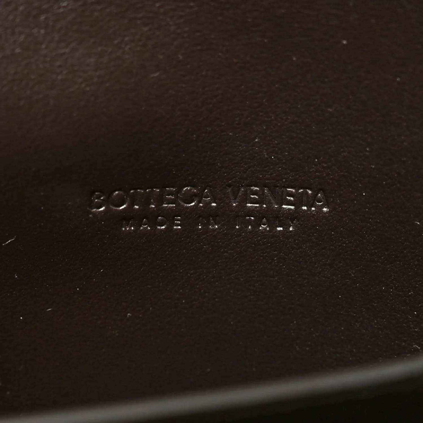 Embossed brand text on dark leather interior of clutch bag