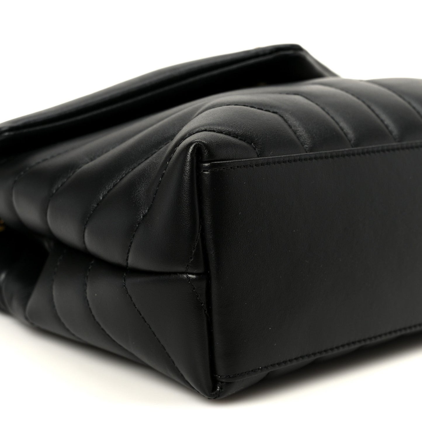 Black quilted leather satchel corner with rounded seam and smooth panel detail.