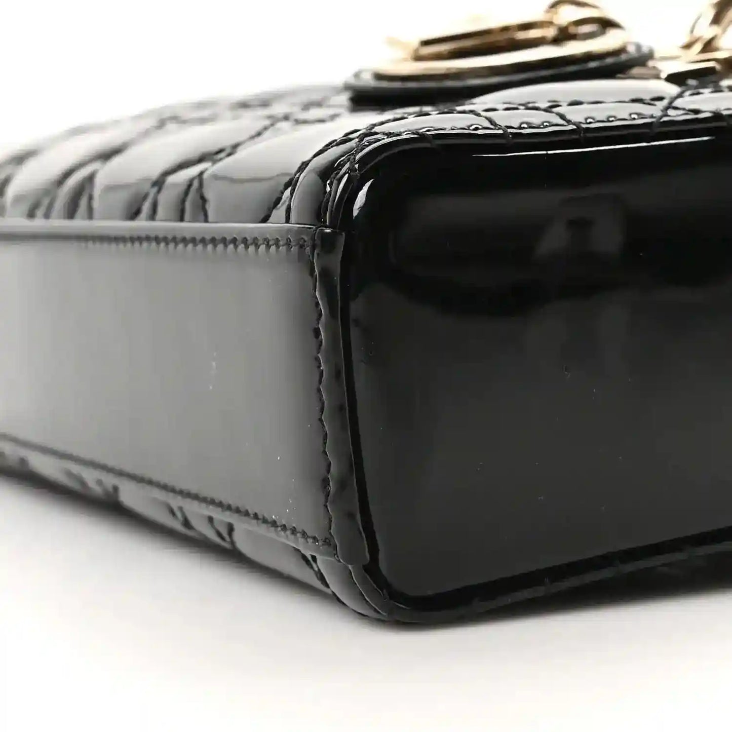 Black patent leather bag side panel with glossy finish and stitched border