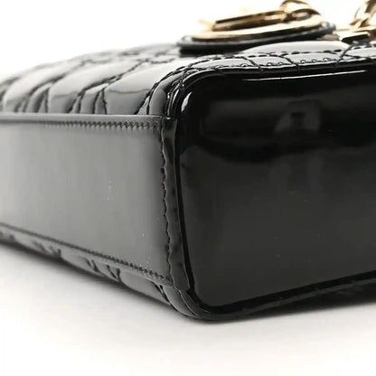 Black patent leather bag side panel with glossy finish and stitched border