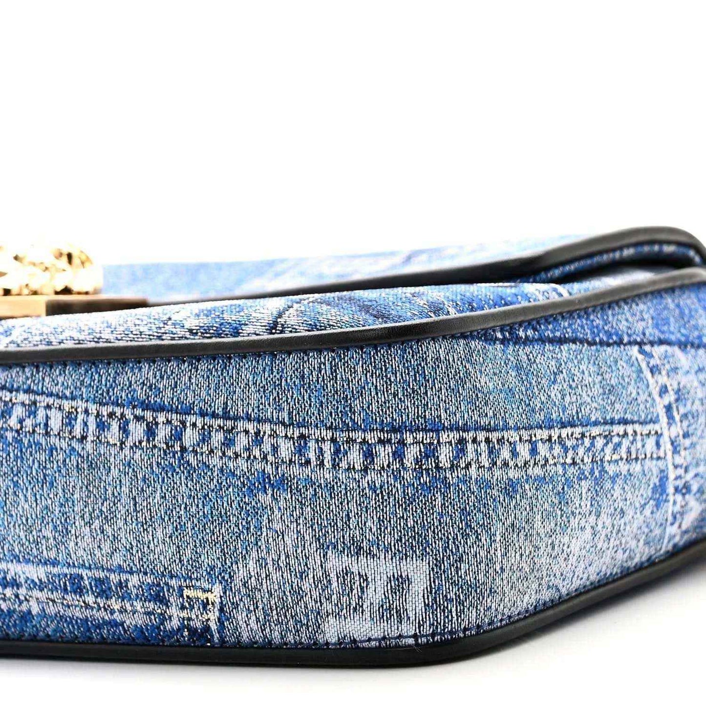 Blue denim baguette bag close-up of black-trimmed edge and patchwork stitching