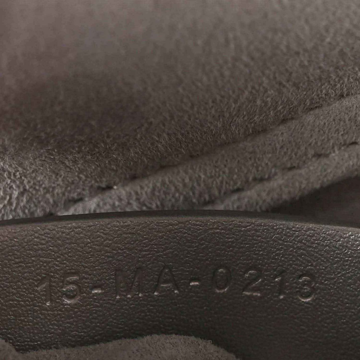 Leather serial stamp on handbag lining with raised numbers and letters.