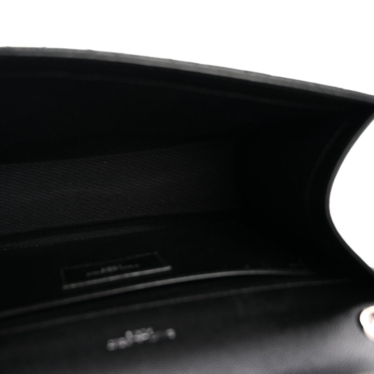Black satchel interior opening with stitched edge and small logo plaque