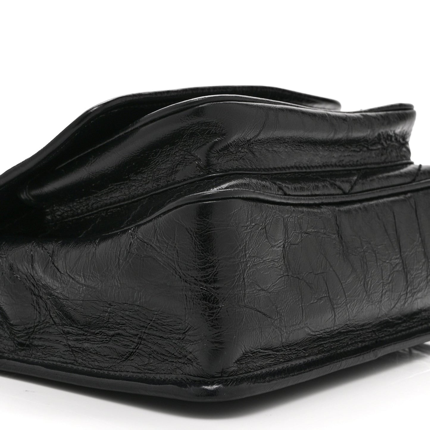 Black satchel bag side view with crinkled leather texture and flap edge