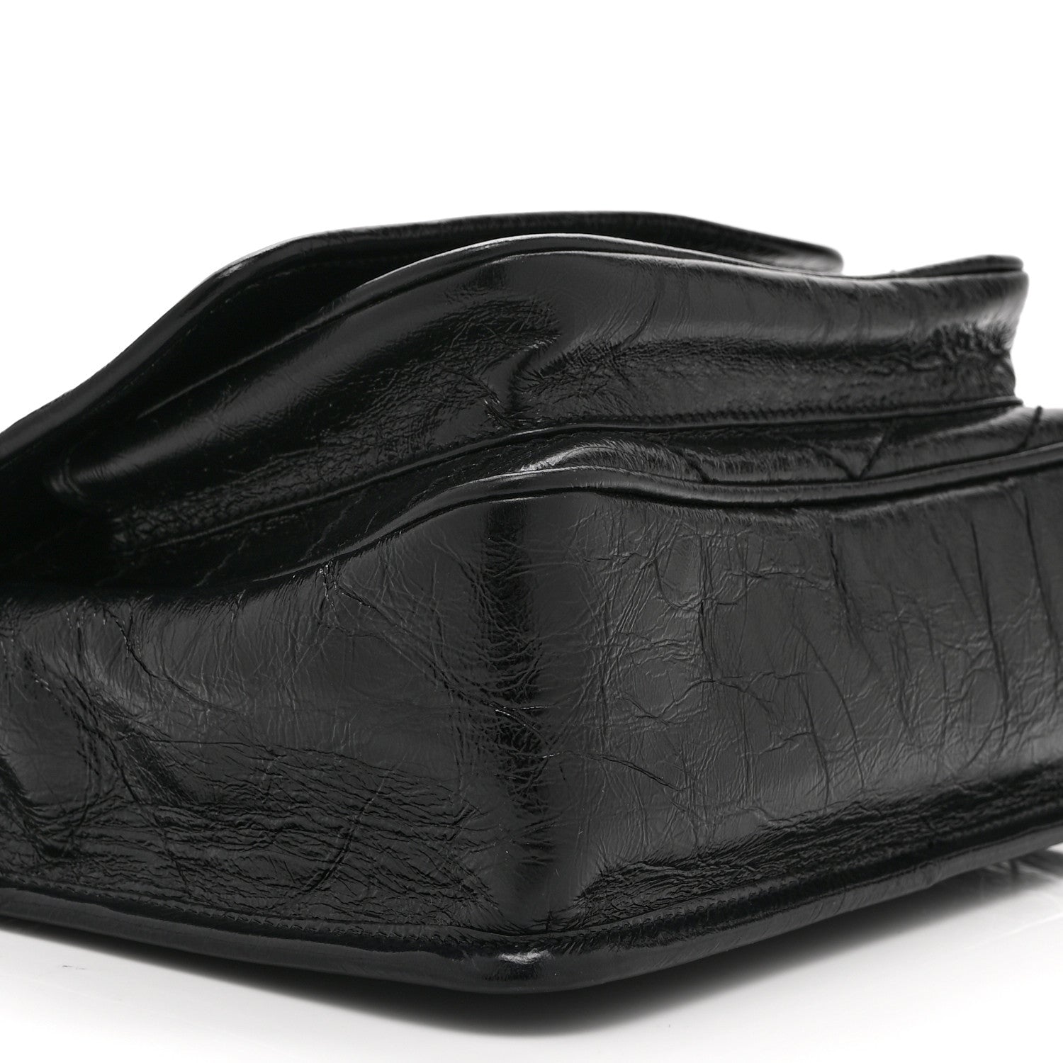 Black satchel bag side view with crinkled leather texture and flap edge