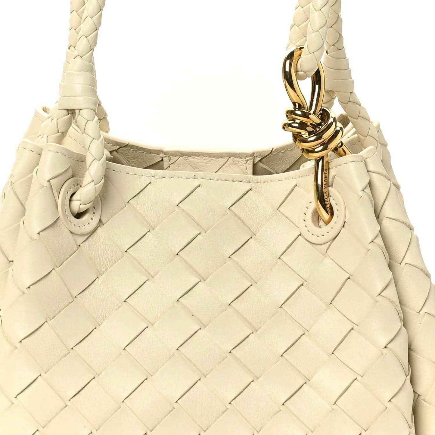 Light cream woven shoulder bag close-up with gold clasp and braided strap ends