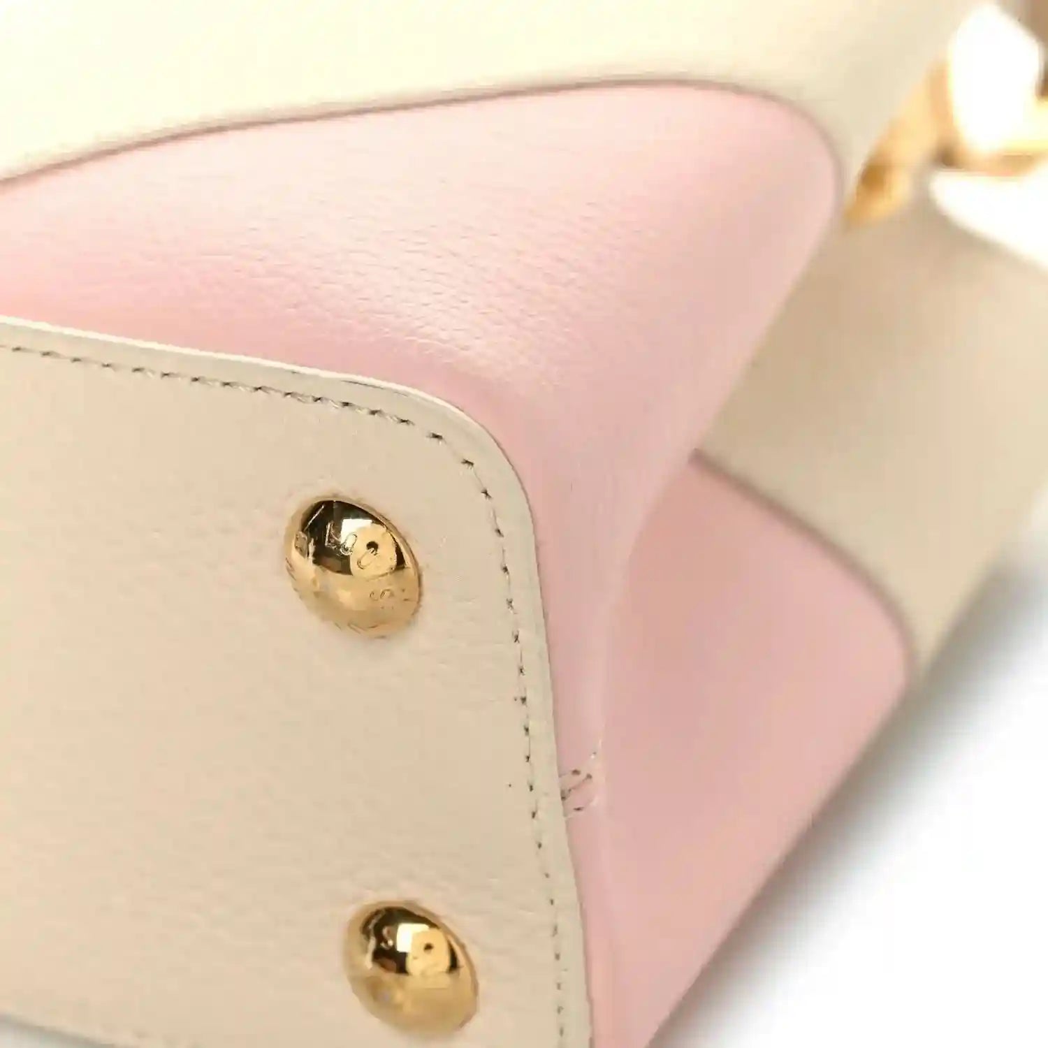 Beige leather handbag corner with two gold snap buttons and blush pink panel