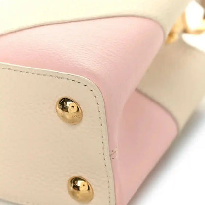 Beige leather handbag corner with two gold snap buttons and blush pink panel