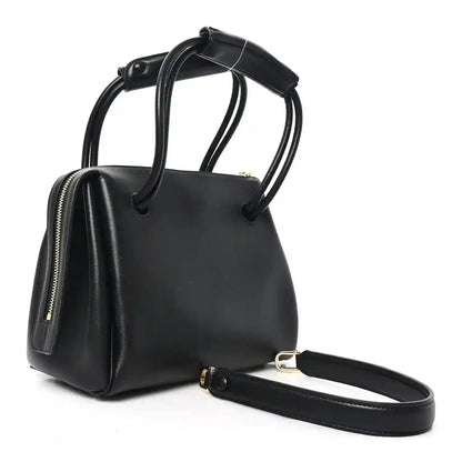 Small black leather handbag with zip top, curved handles, and crossbody strap