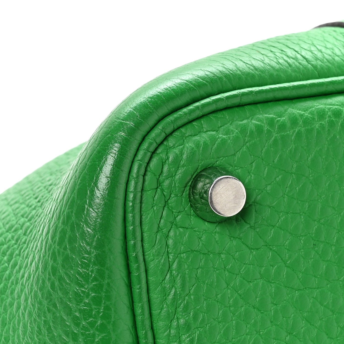 Green leather tote bag, close-up of round turn-lock and textured grain