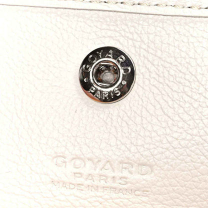 White pebbled leather strap end with round metal snap hardware labeled Goyard