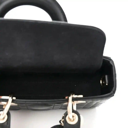 Black lambskin handbag with gold hardware and smooth trim, close-up