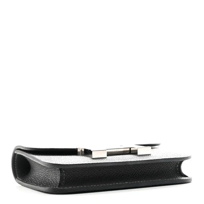 Constance slim wallet profile view in dark textured leather with H clasp hardware