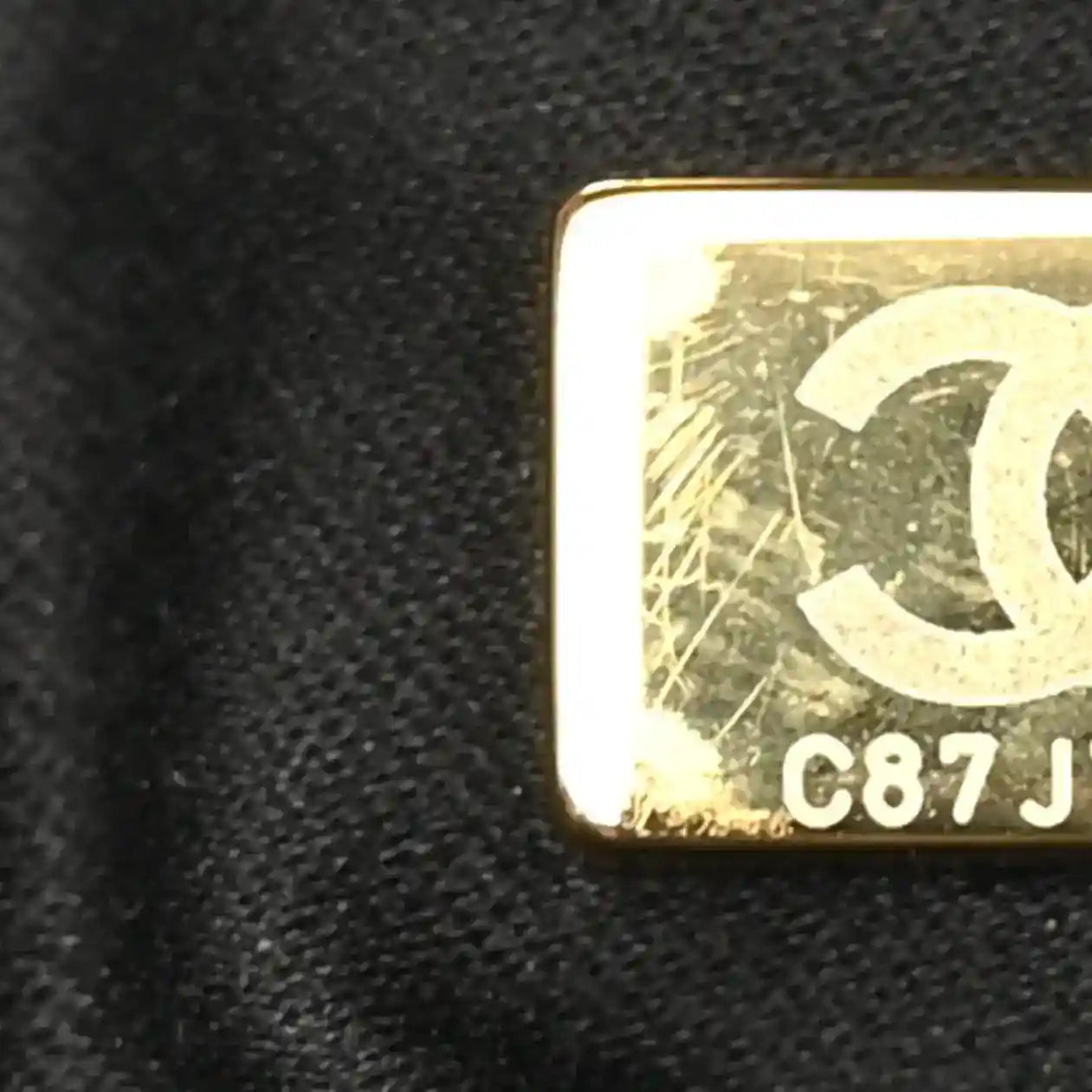 Gold-tone label showing CB7J on Chanel black leather hardware