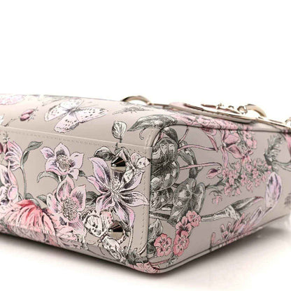 Small Lady Dior handbag side view with pink floral print, strap and metal clasp