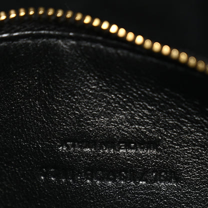 Close-up of black leather with subtle embossed text and gold zipper trim.