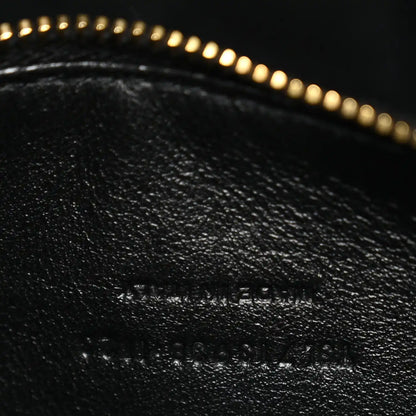 Close-up of black leather with subtle embossed text and gold zipper trim.