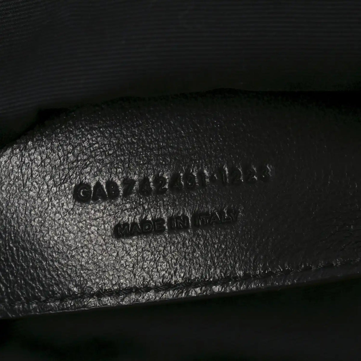 Embossed text on black leather interior of shoulder bag, includes MADE in Italy
