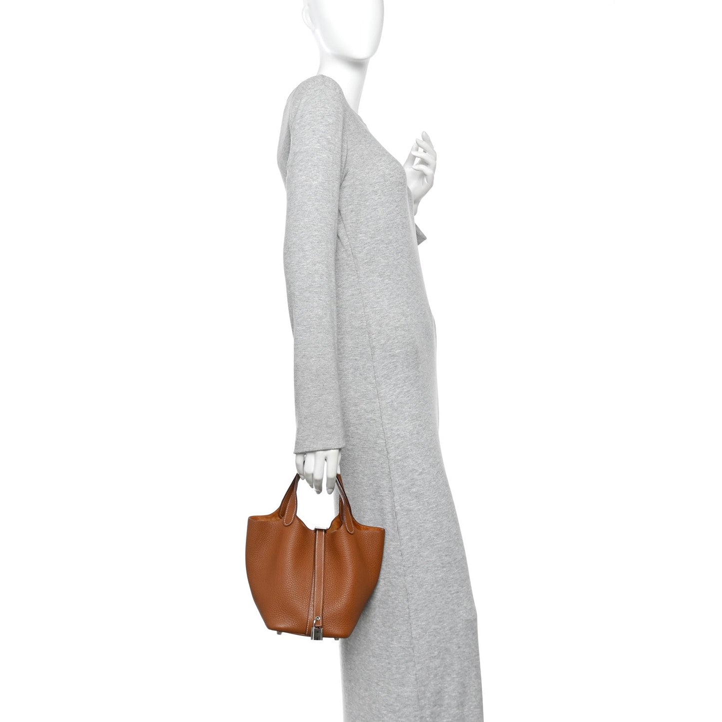 Cognac brown mini tote bag with top handles, shown worn with long gray sleeve