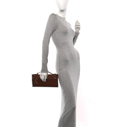 Loro Piana smooth calfskin clutch in burnt tan, held by model at side