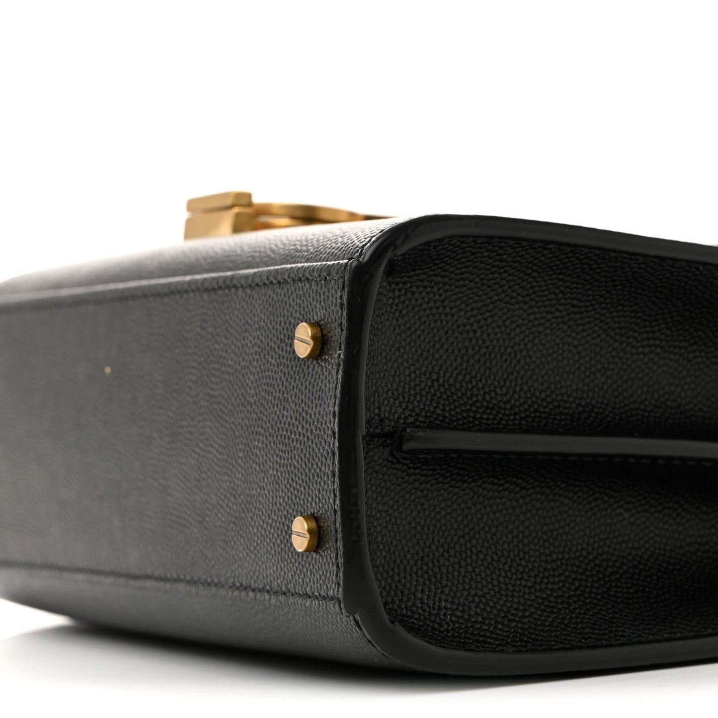 Black leather mini bag corner close-up with gold-tone stud hardware.