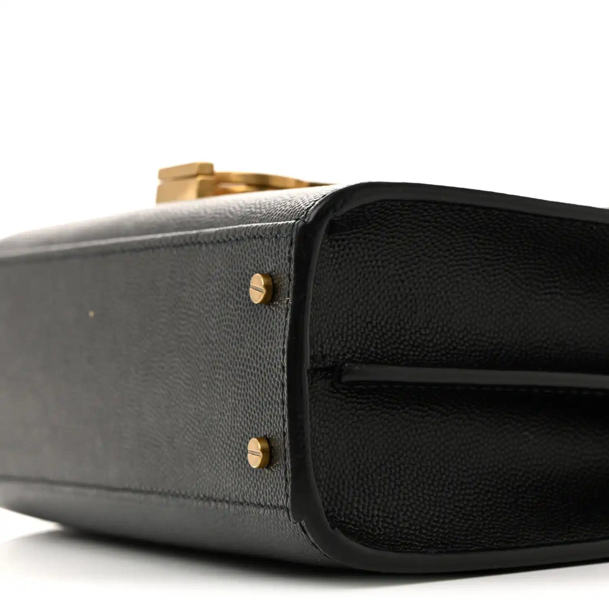 Black leather mini bag corner close-up with gold-tone stud hardware.
