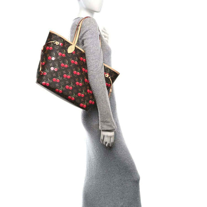 Cherry-print monogram tote bag worn on model, showing handles and shoulder strap.