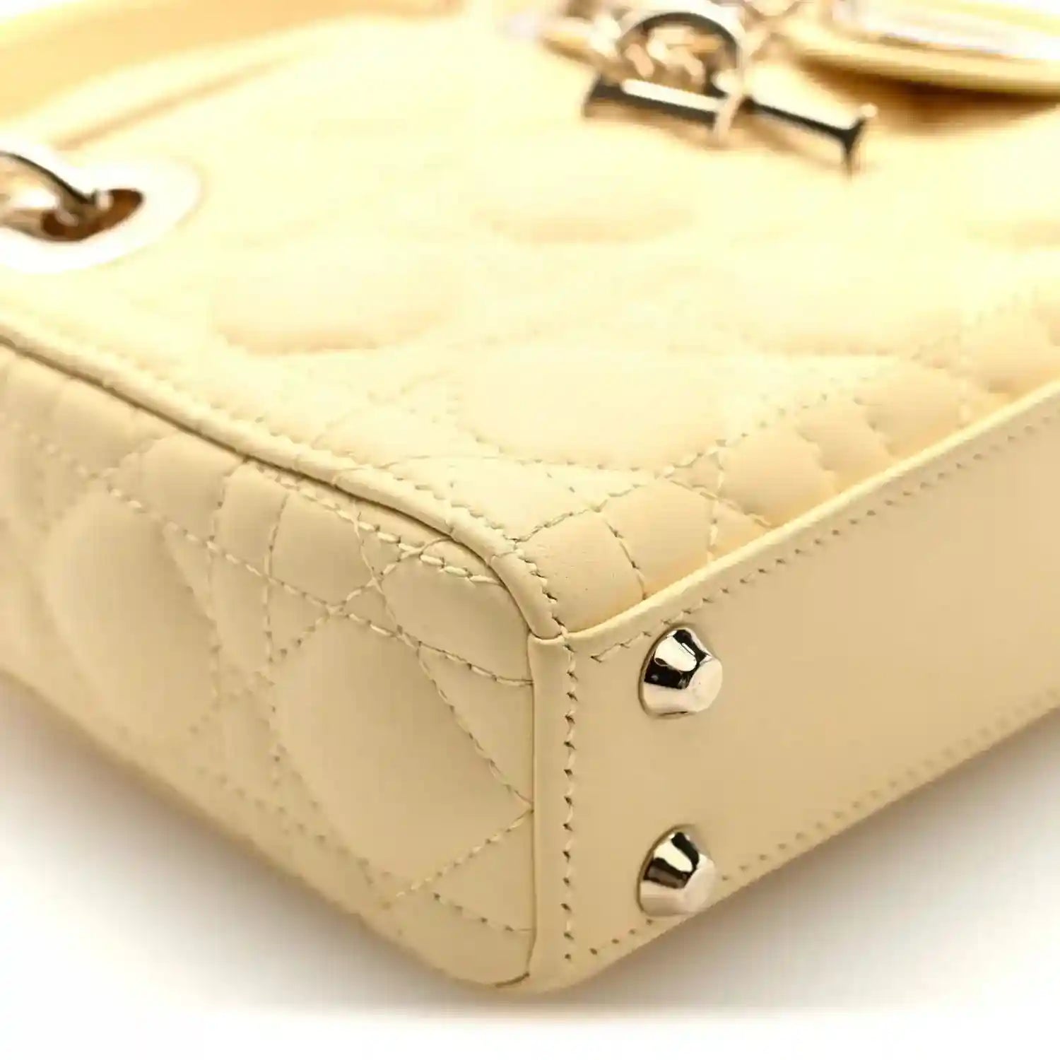 Soft yellow handbag corner detail with cannage stitching and silver-toned stud feet