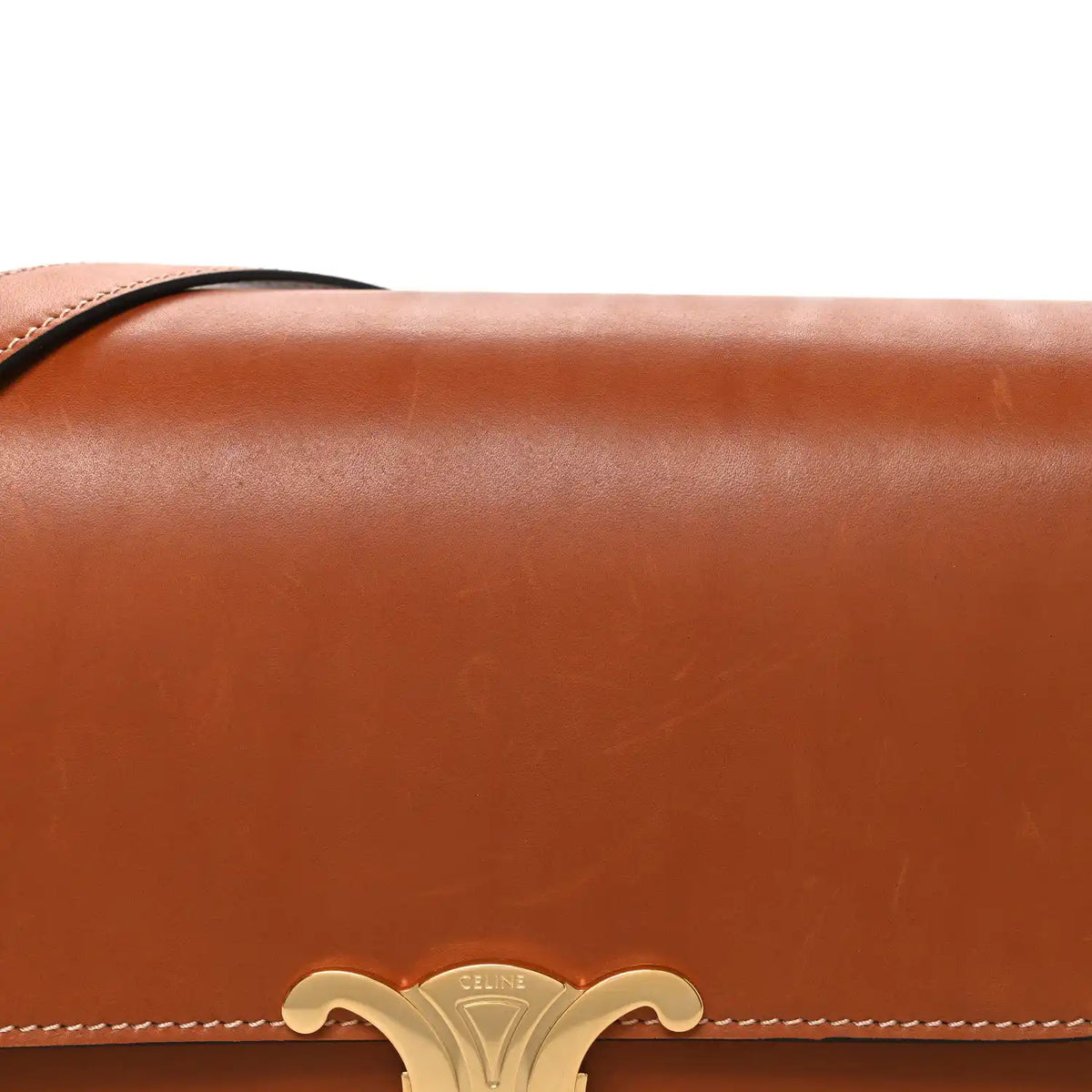 Tan shoulder bag flap with gold-tone Celine emblem and braided edge stitching.