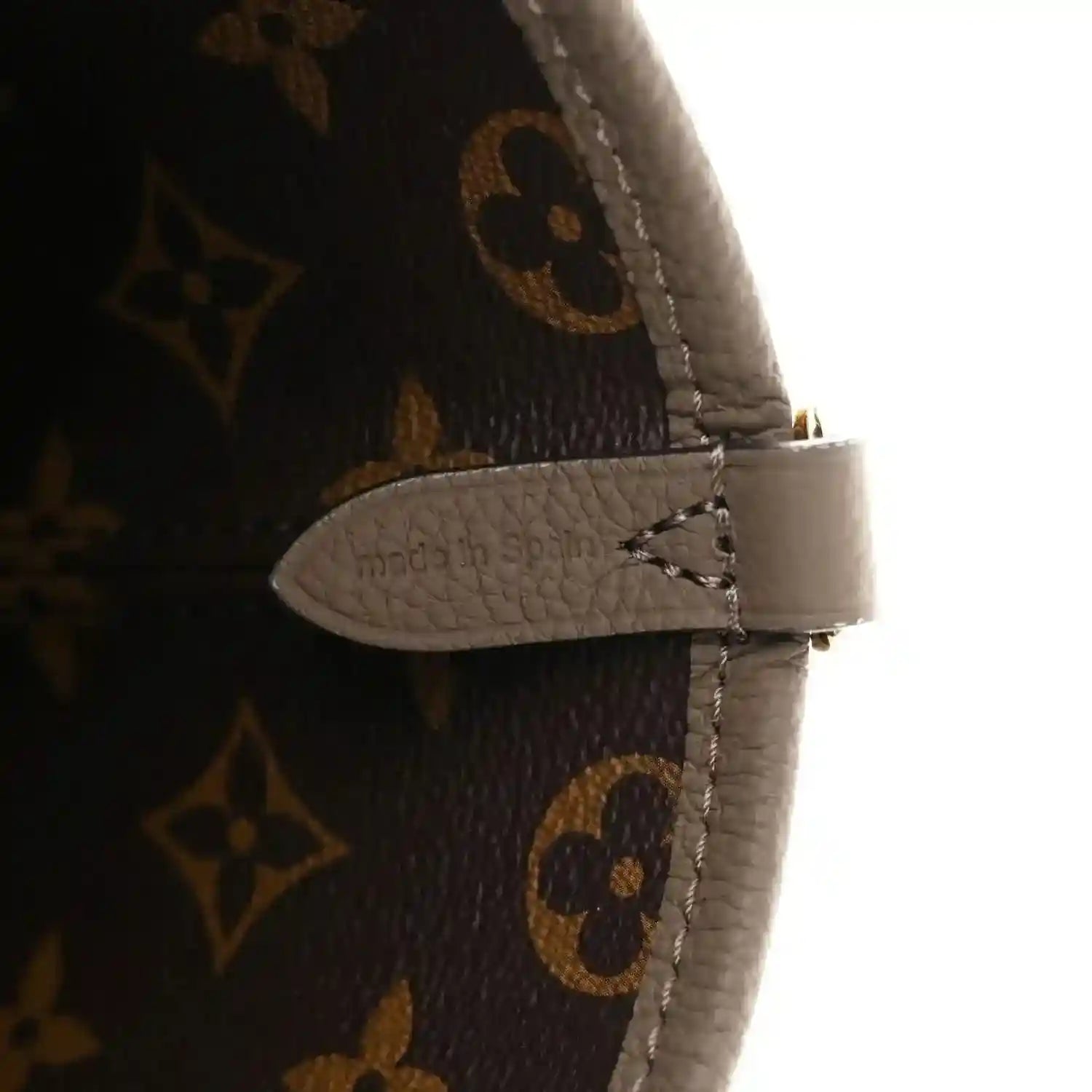 Monogram canvas bag strap end with gray leather tab and visible stitching detail