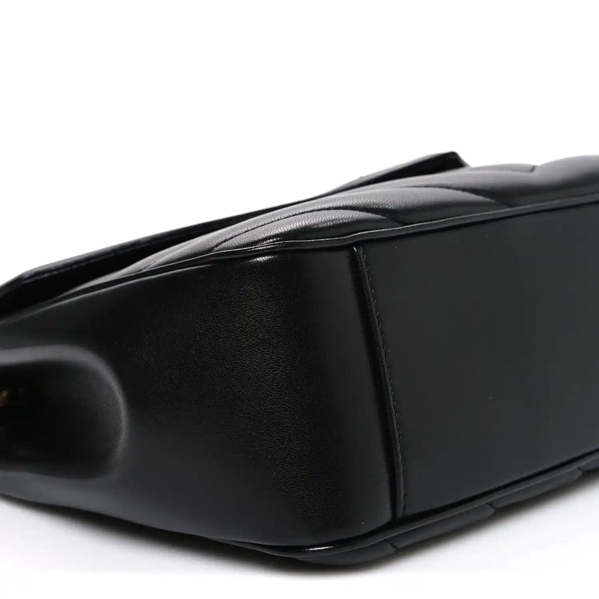Black leather shoulder bag end panel with smooth edge and subtle grain texture