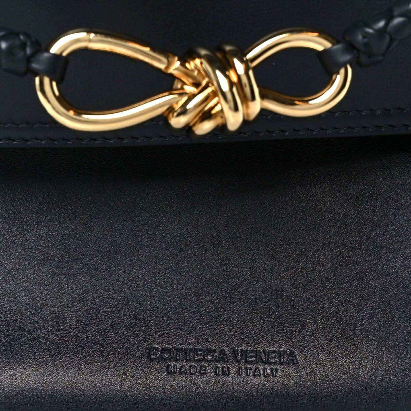 Black handbag with gold-tone ring-and-knot detail and embossed brand mark