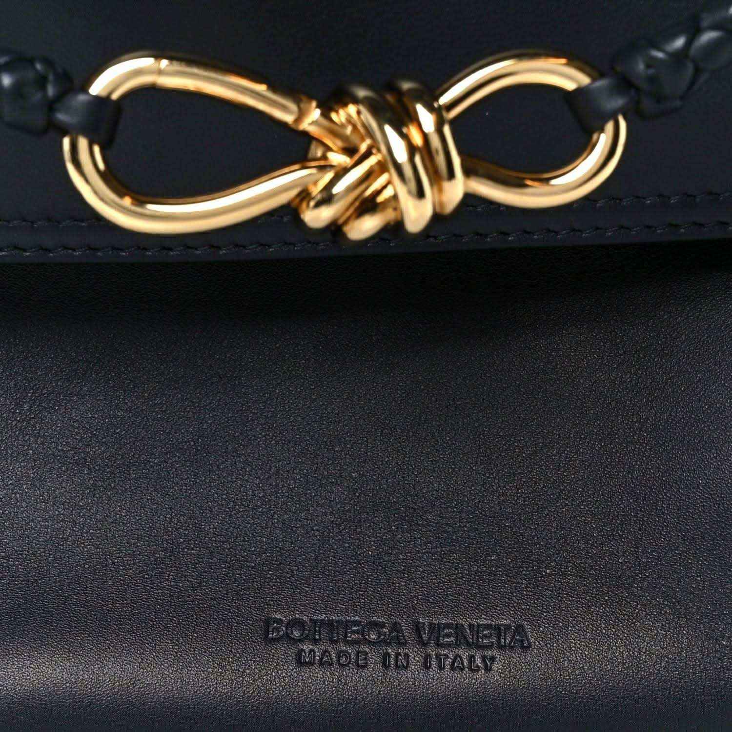 Black handbag with gold-tone ring-and-knot detail and embossed brand mark