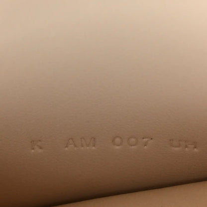Stamped code on light cream leather, faint marks visible
