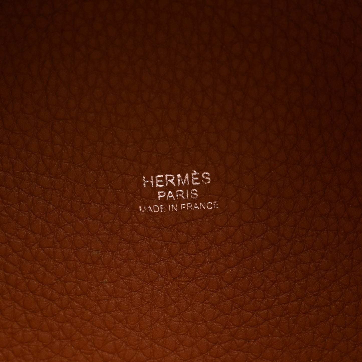 Cognac brown pebbled leather panel with stamped brand text