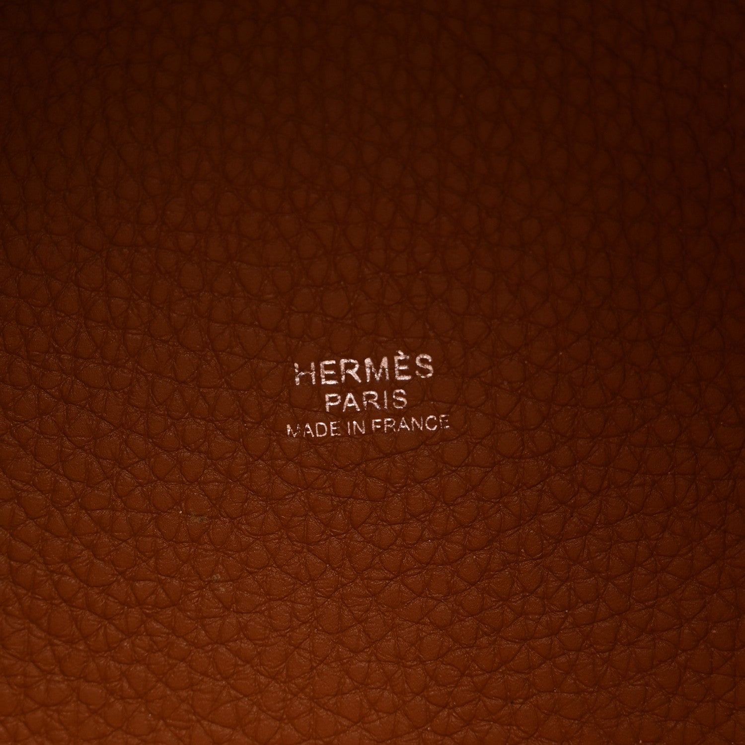 Cognac brown pebbled leather panel with stamped brand text