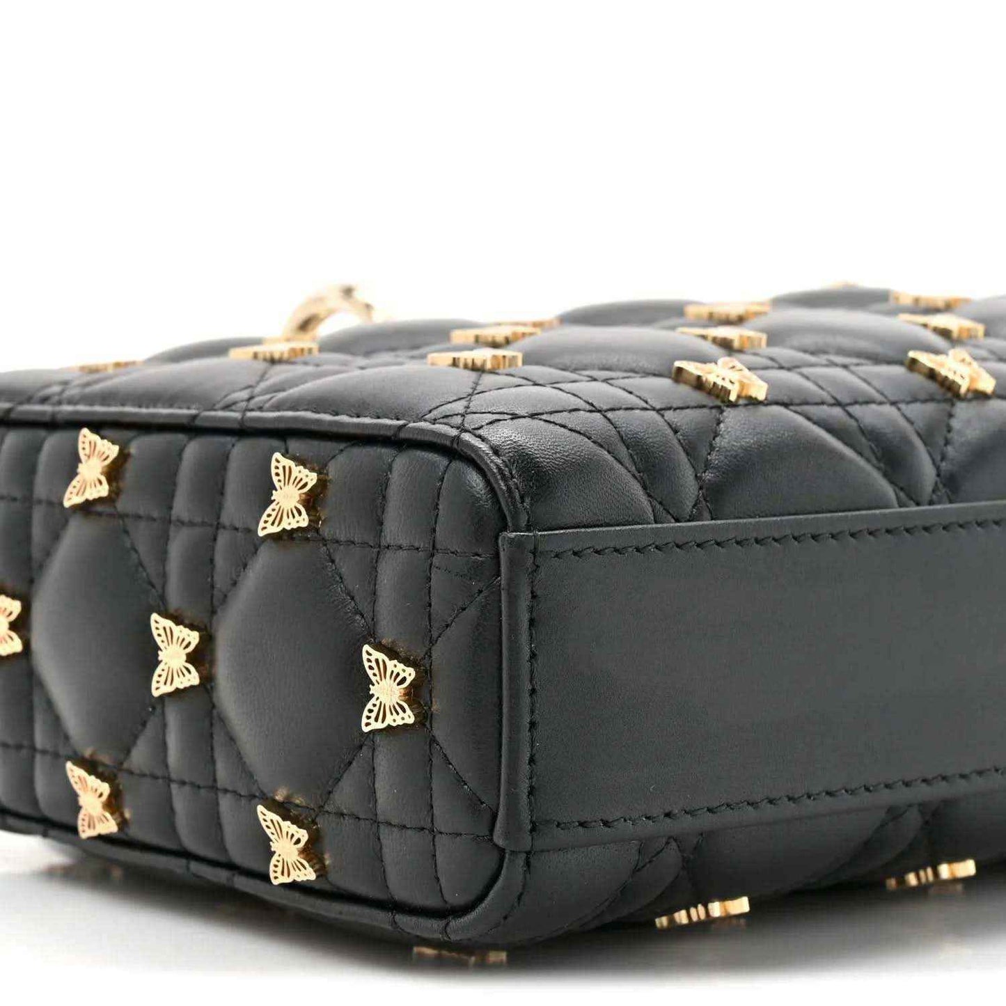 Black quilted lambskin top handle bag with butterfly charms and gold hardware, side view