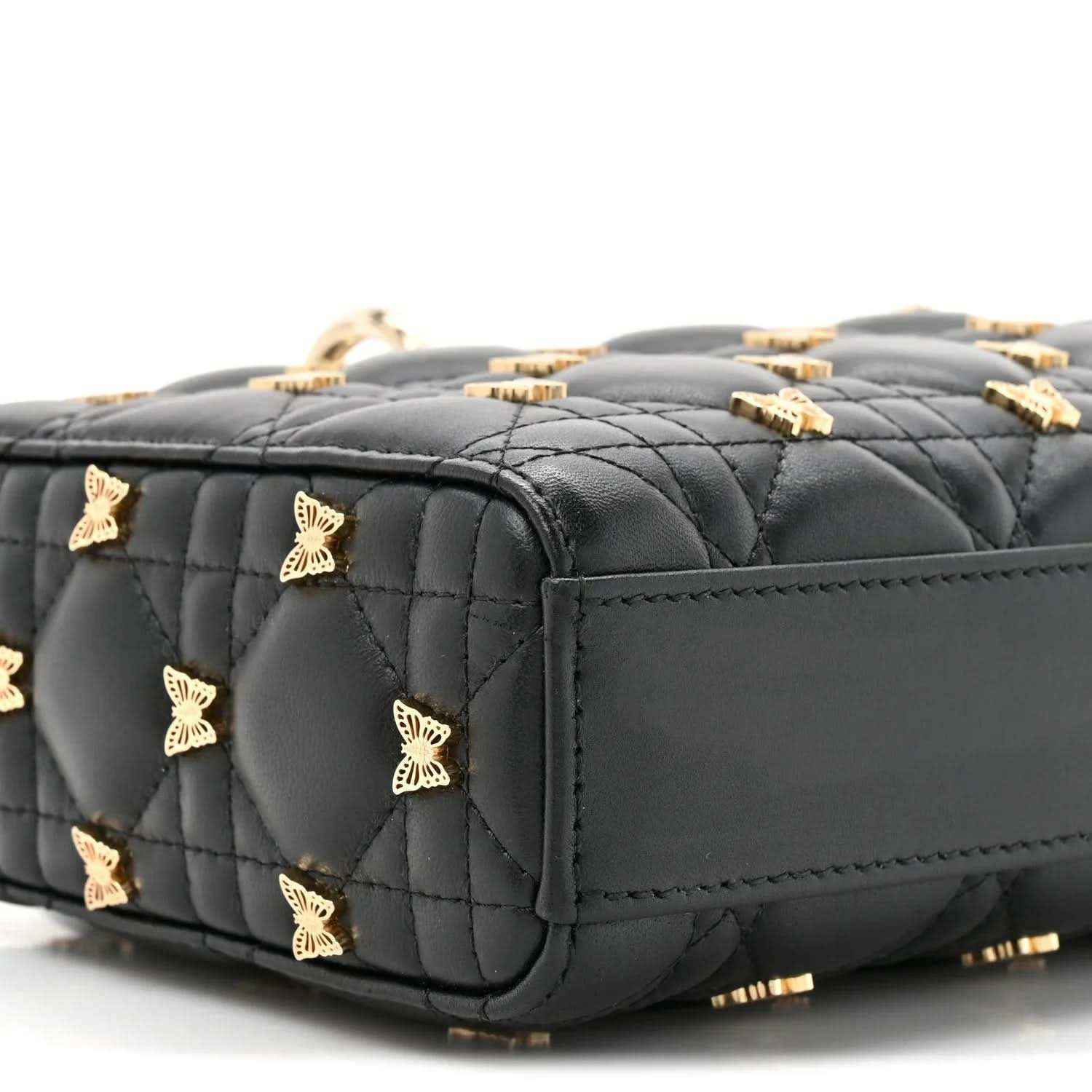 Black quilted lambskin top handle bag with butterfly charms and gold hardware, side view