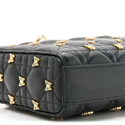 Black quilted lambskin top handle bag with butterfly charms and gold hardware, side view