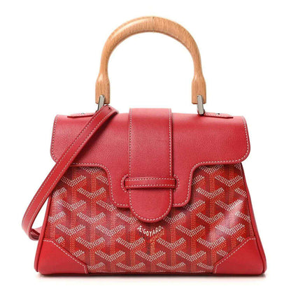 Red mini handbag with top handles, shoulder strap, flap, and patterned coated canvas.