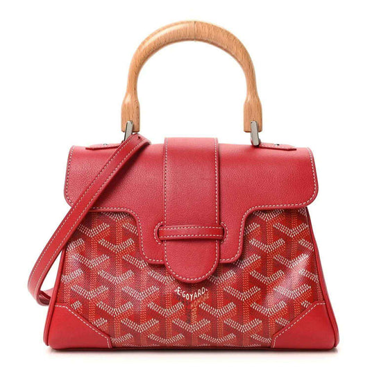 Red mini handbag with top handles, shoulder strap, flap, and patterned coated canvas.