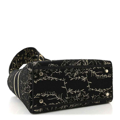 Black embroidered handbag with gold floral pattern, front snap closure and side studs