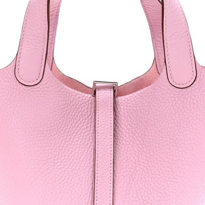 Rose pink leather handbag close-up of top handles and central lock bar