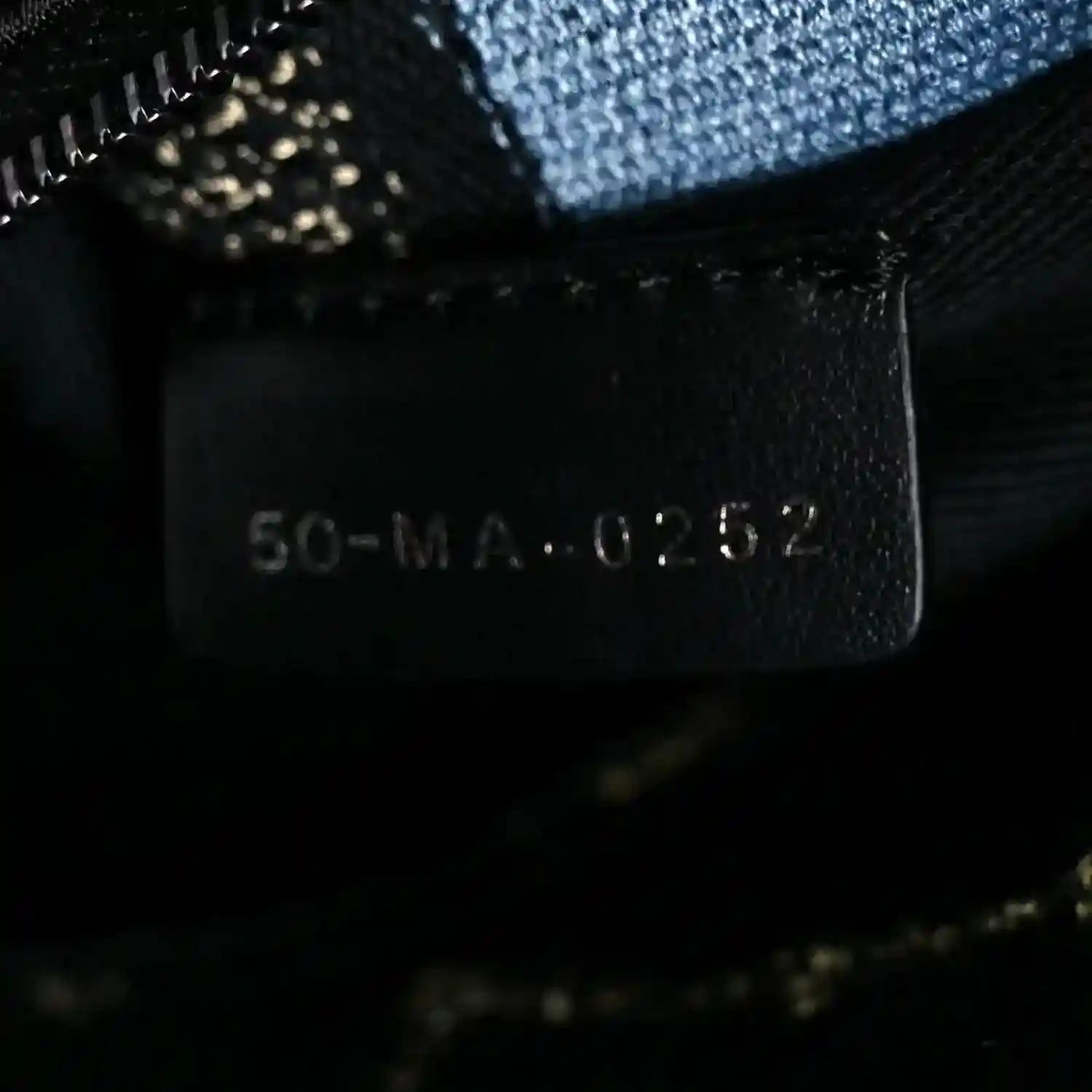 Handbag style label with code '50-MA-0-2-8' on dark fabric