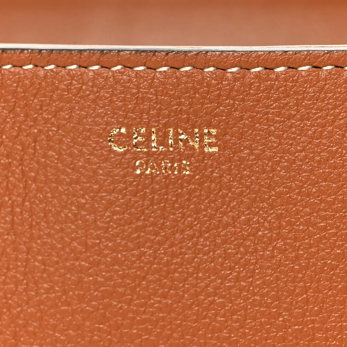 Tan grained calfskin close-up with embossed CELINE branding and stitched edge